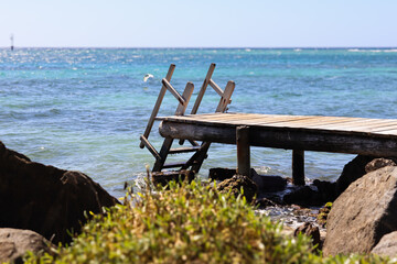 Dock with stairs leading into the blue Aruban ocean.