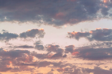 Dramatic cumulus clouds on sunny day at sunset painted in red and purple with sun. Atmosphere multicolor natural background or wallpaper