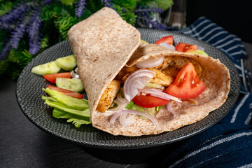 Wholegrain tortilla wraps with vegetables and chicken on a plate.