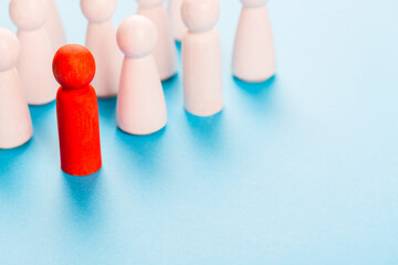 Red human figurine near white human figurines. Leadership in business concept.