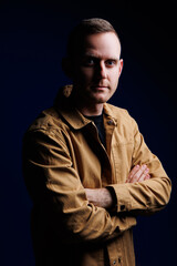 Portrait of a confident man on a dark background in a brown shirt. The emotion of concentration. A man without a smile