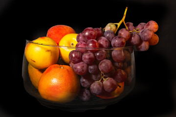Still life of tropical fruits in a glass container. Includes grapes, apples, oranges, papaya.