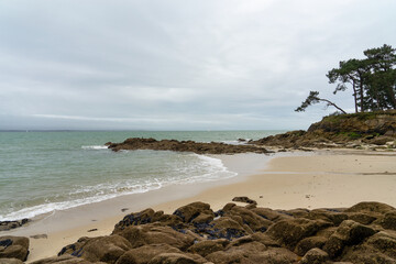 Fototapeta na wymiar Plage de sable longeant l'océan Atlantique dans le Finistère sud, Bretagne, agrémentée de rochers, offrant un paysage maritime pittoresque.