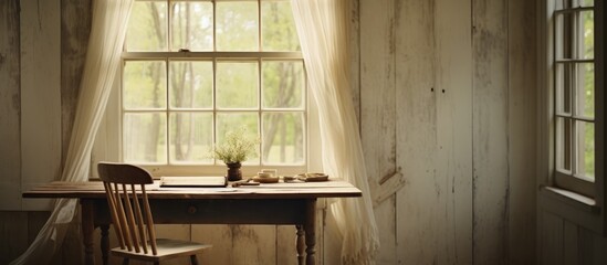 A room in a rustic white farmhouse featuring a small table and a chair placed next to a tall window. The wooden table is simple yet elegant, complemented by the matching chair.