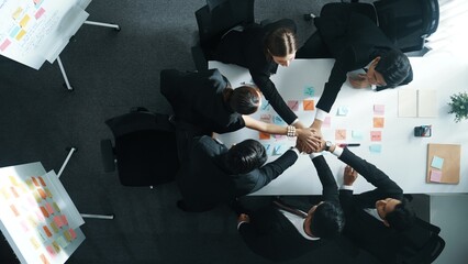 Top down aerial view of professional investor team putting hand together. Skilled diverse business...