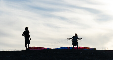 Man with his paragliding teacher learning how to take off to fly a paraglider. Backlit photo with...
