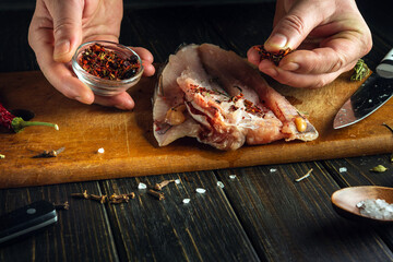 Adding spices to a cut sea fish carcass. Concept of preparing fish dish on table in saloon.