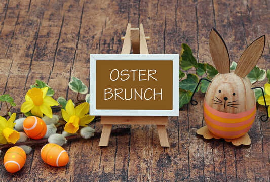 Der Text Osterbrunch auf ein Schild geschrieben mit Osterdekoration und Blumen.	