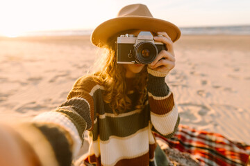 Pretty woman with a professional photographer taking selfie on the beach at sunset. Travel blog.  Adventure, vacation concept.