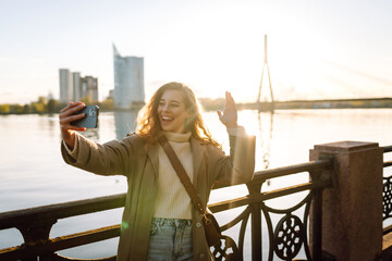 Happy woman with a mobile phone, takes a selfie, communicates with friends, blogs outdoor. Lifestyle, travel, tourism, nature, active life. - obrazy, fototapety, plakaty