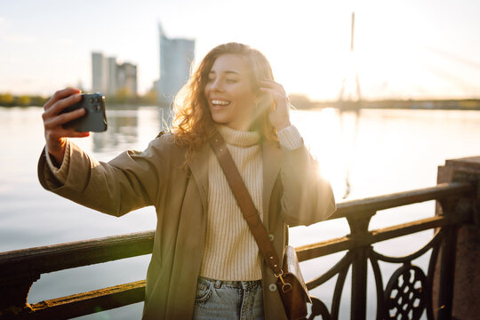 Happy woman with a mobile phone, takes a selfie, communicates with friends, blogs outdoor. Lifestyle, travel, tourism, nature, active life.