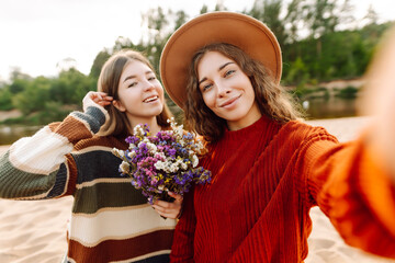 Obraz premium Happy women taking selfie on the beach. Spring weather. Holidays, technology, blogging concept.