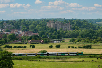 Arundel Castle overlooking green countryside with commuter train passing through