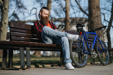 Remote working concept with a male entrepreneur using a tablet outdoors next to his bike in a city...