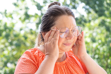 mature woman 50-55 years old holds on to temples, close up female face with facial expression...