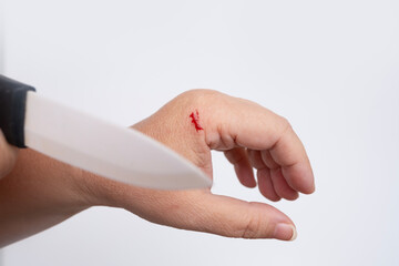 drop of red blood, close-up of female hand, wound from cut, kitchen knife with porcelain blade,...