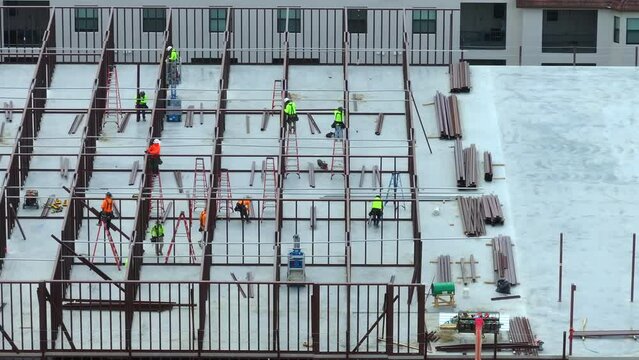 Development of commercial housing in USA. Construction works on monolithic frame. Large building site with scattered workers and equipment. Real estate market.