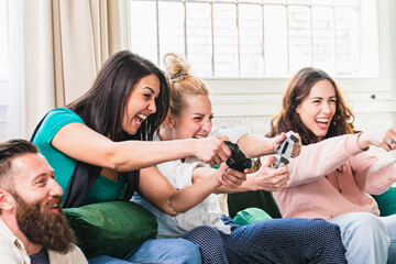 excited friends having fun playing video games on the couch
