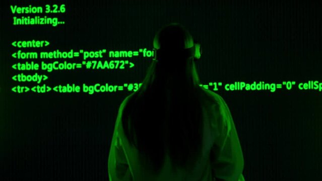 Person against big digital wall in studio. Woman hacker in virtual reality glasses in front of digital screen cyber graphic code data visual background.