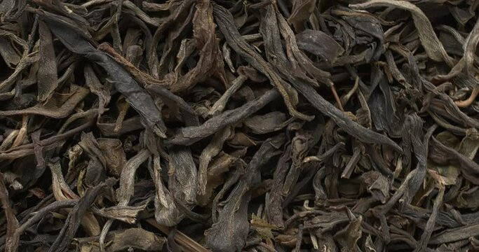 Close-up view of chinese raw maturing (mao cha) green Pu Erh dried tea leaves as an abstract food background. Table spin.