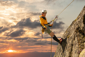 Person climbing in high mountains with yellow jacket rope and helmet in nature, confidence and risk, safety - obrazy, fototapety, plakaty