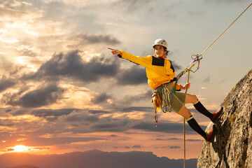 woman climbing in the mountain at sunset with lus rays, security, confidence business woman, rope access, life insurance.