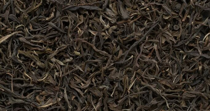 Chinese raw maturing (mao cha) green Pu Erh dried tea leaves as an abstract food background. Table spin.