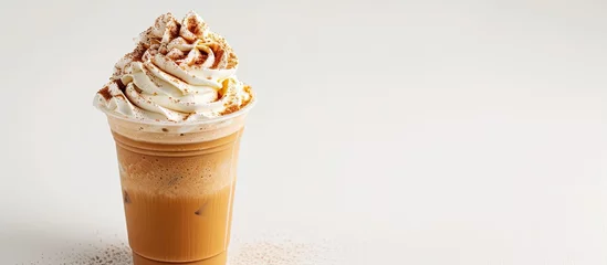 Rucksack A white background showcases a frappe cup filled with a steaming cup of coffee topped with a generous swirl of whipped cream and a sprinkling of cinnamon powder. The creamy texture of the whipped © AkuAku