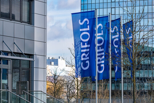 satin flags with letters GRIFOLS fluttering on silk cloth, global healthcare company develops plasma-derived medicines, innovative biopharmaceutical solutions, Frankfurt, Germany - February 13, 2024