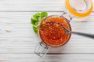 Red caviar in jar with fresh parsley