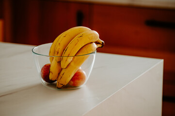 Bright daylight highlights a banana in a glass bowl on the kitchen counter
