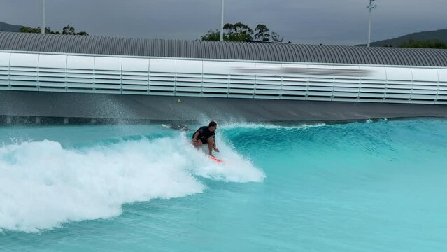 Beginner surfer rides the artificial wave and trains in the surfing pool