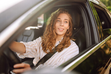 Female driver. Portrait of young beautiful woman in  sweater sitting in the car. Car travel, tourism, carshering concept.