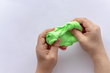 The child sculpts green plasticine with his hands.
