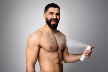 Fototapeta premium Shirtless young bearded middle eastern man using deodorant spray