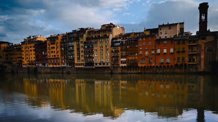 A serene view capturing the vibrant reflections of colorful facades of buildings on the calm water of a river, Firenze