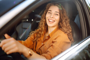 Female driver. Portrait of young woman is driving a car and smiling. Automobile travel.