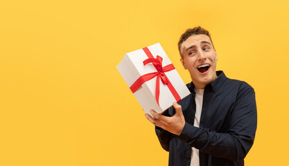Excited young guy holding white gif box with red bow