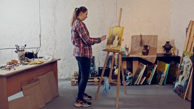 Young female painter creates with passion in a cozy workshop. 