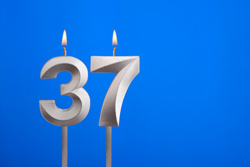 Birthday number 37 - Candle lit on blue background