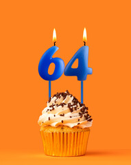 Blue candle number 64 - Birthday cupcake on orange background