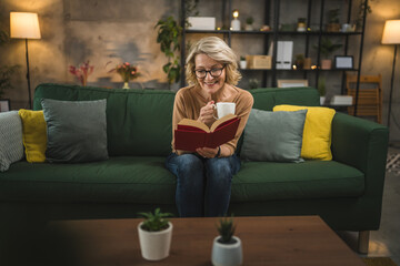 Obraz premium One woman mature caucasian female read book at home wear eyeglasses
