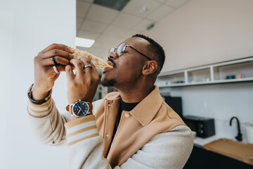 Workday intensity meets pizza delight as a black dude relishes a cheesy slice, turning the break into a flavorful escape from the grind. - obrazy, fototapety, plakaty