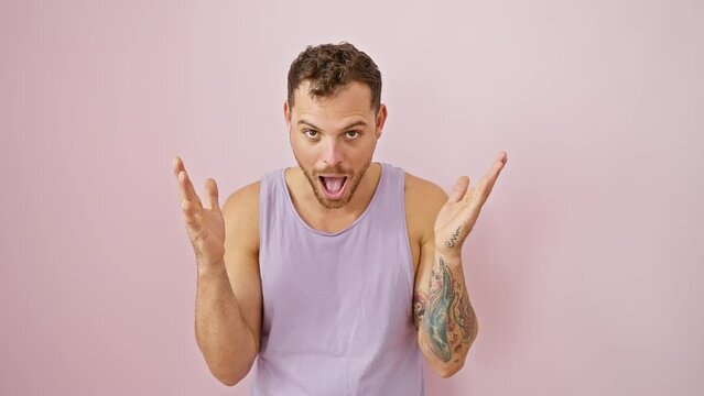 Stunned young man in sleeveless tee over pink! surprise filled face, open mouthed in amazed disbelief, naturally amusing and excited expression.