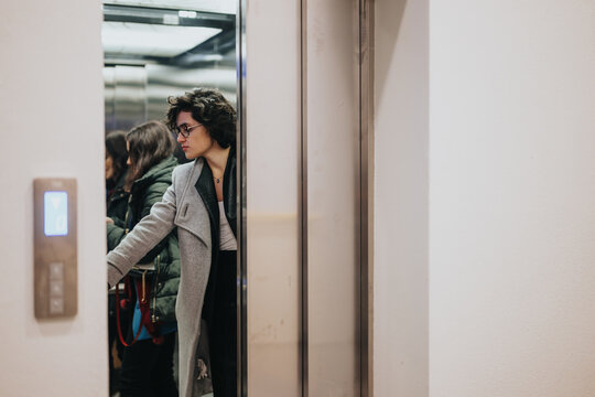 Young woman exiting elevator into busy urban environment, contemplative.