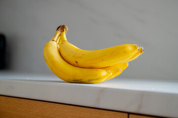 Banana positioned on the kitchen table, illuminated by daylight - 747591650