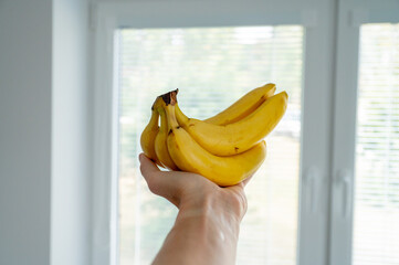Man's hand holding bananas, natural daylight - 747592225