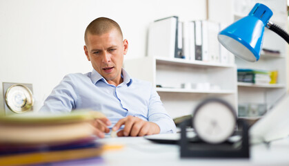 Portrait of carefree lazy office worker sitting at workplace playing with coin