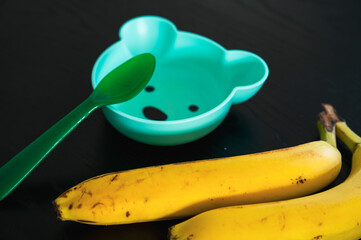 Banana and baby bowl in the shape of a bear. Feeding a toddler with fruit - 747595017
