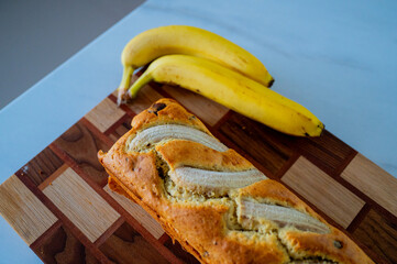 On the kitchen counter: banana bread and a ripe banana in natural daylight - 747595284